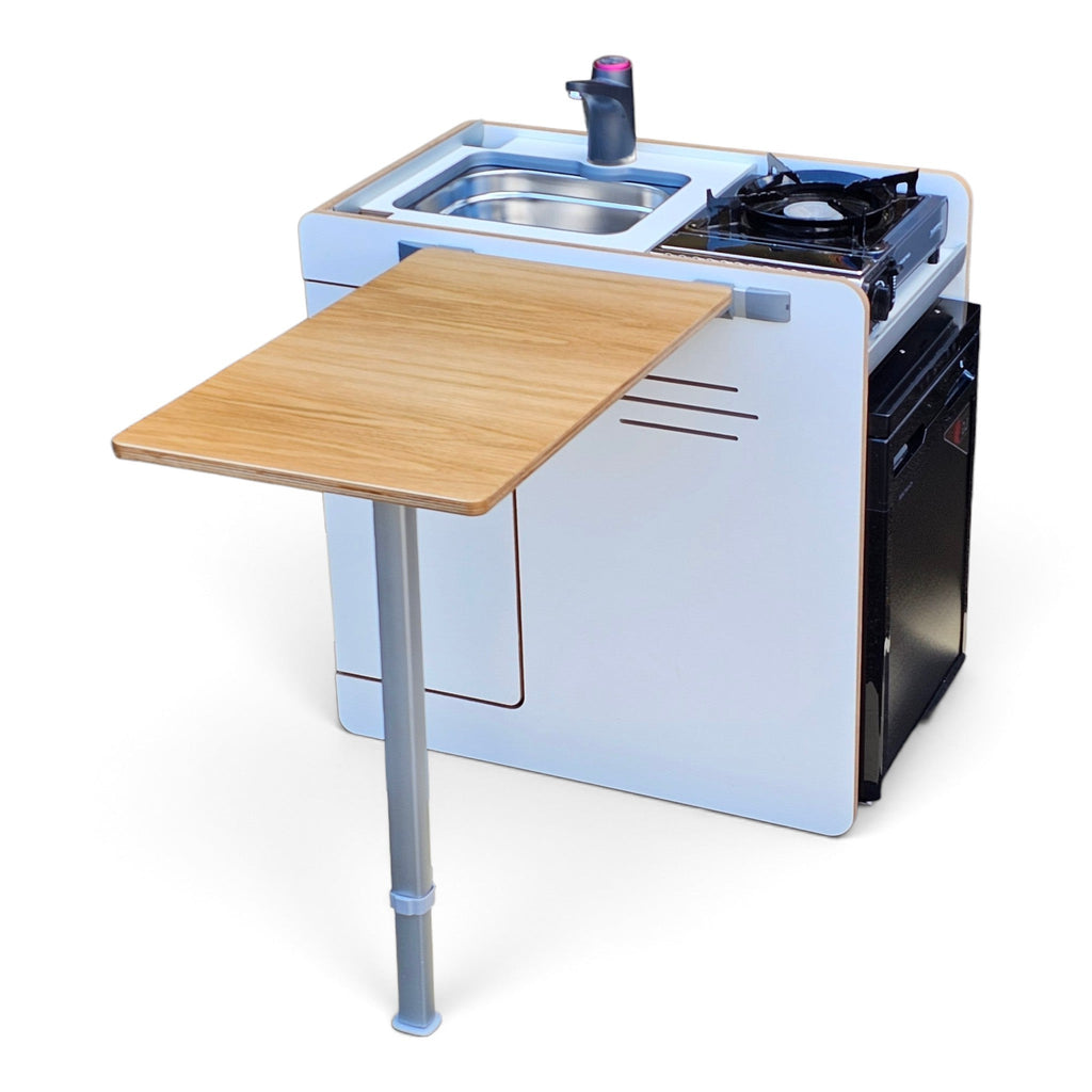 Compact white and black camping kitchen unit with an attached wooden folding table on a metal stand, shown on a clean white background.